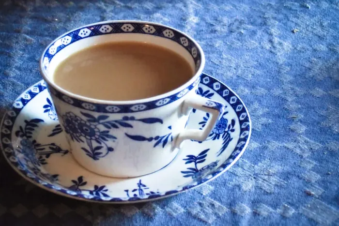 Framed Print : Antique blue and white cup and saucer of Indian tea with milk, on blue tablecloth