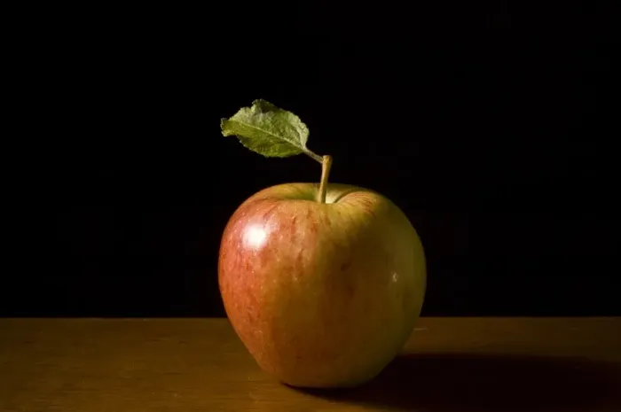 Framed Print : Apple with leaf on wooden surface against black background credit: Marie-Louise Framed Print : Apple with leaf on wooden surface against black background credit: Marie-Louise