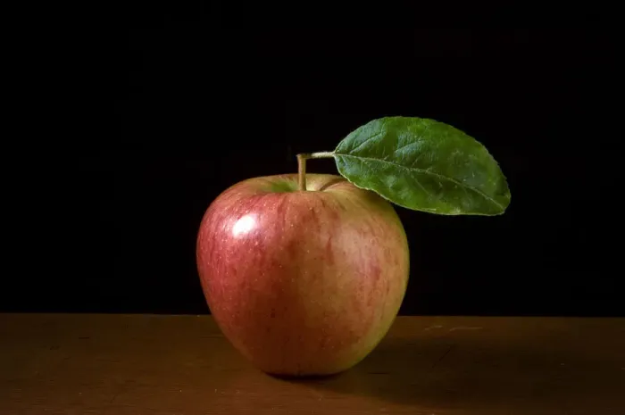Framed Print : Apple with leaf on wooden surface against black background credit: Marie-Louise