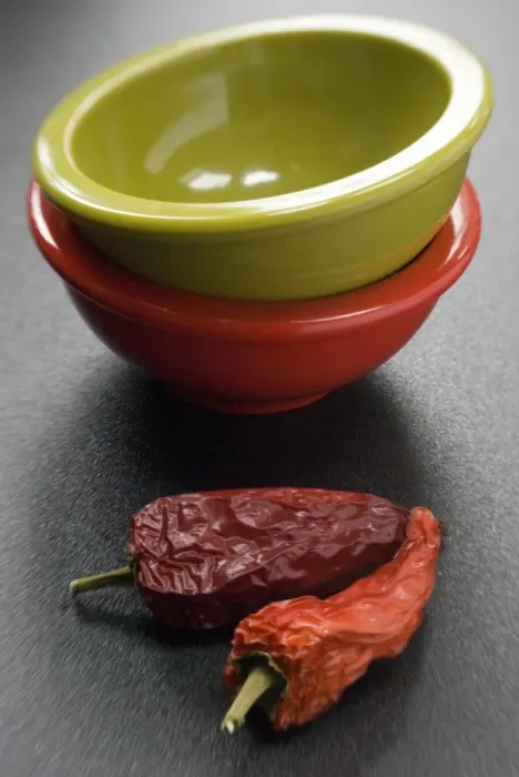 Framed Print : Two bright melamine bowls stacked on dark surface with two red hot chilli peppers Framed Print : Two bright melamine bowls stacked on dark surface with two red hot chilli peppers