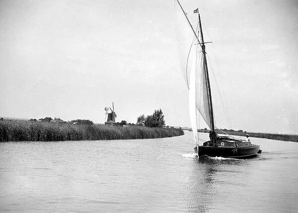 The Broads, Norfolk. Wherry sailing on a river  /  canal, a windmill in the background 1934