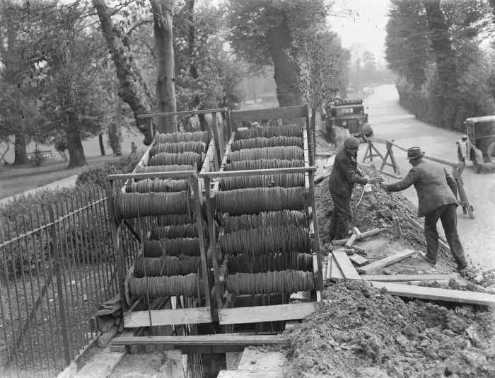 Framed Print : Bundles of telephone cables on a cradle that are being laid underground by workers Framed Print : Bundles of telephone cables on a cradle that are being laid underground by workers