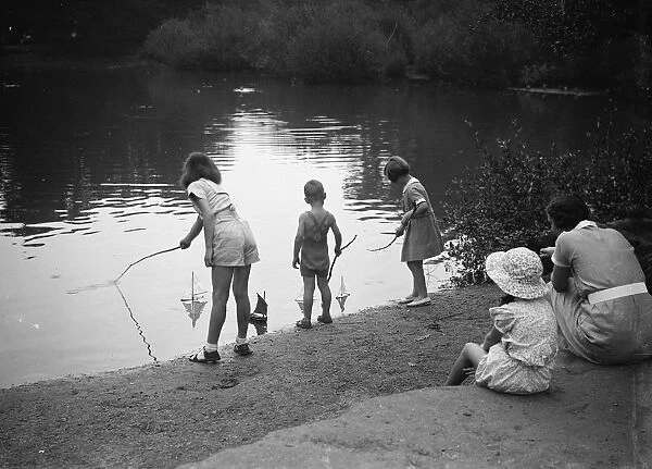 Children play with toy sailing boats in Dartford park. 24 August 1937