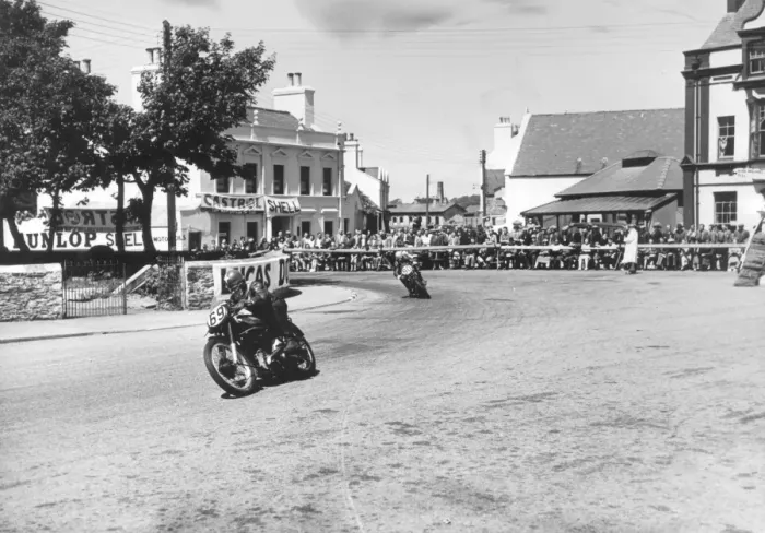 Framed Print : Competitors passing Ramsay Town Square at speed. Number 69 is W. J. Evans on AJS and number 90 is C