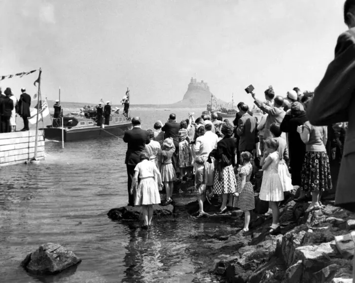 Framed Print : Crowds line the shore on Holy Island as the royal barge approaches the landing stae Framed Print : Crowds line the shore on Holy Island as the royal barge approaches the landing stae