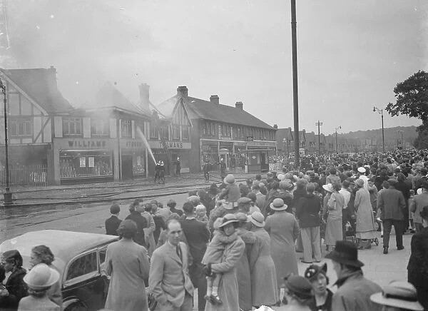 Crowds watch as firemen attempt to put out fires in a parade of shops in Welling, Kent