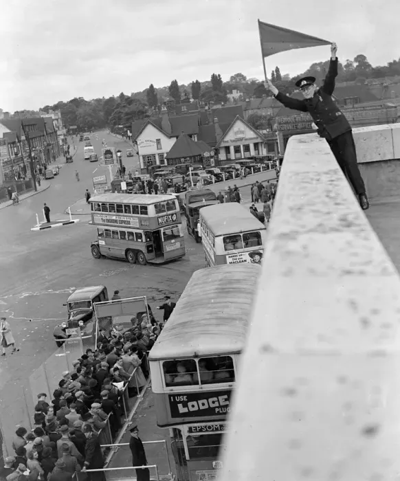 Framed Print : Derby Day in Epsom, Surrey. A Bus official signalling the double - decker buses Framed Print : Derby Day in Epsom, Surrey. A Bus official signalling the double - decker buses