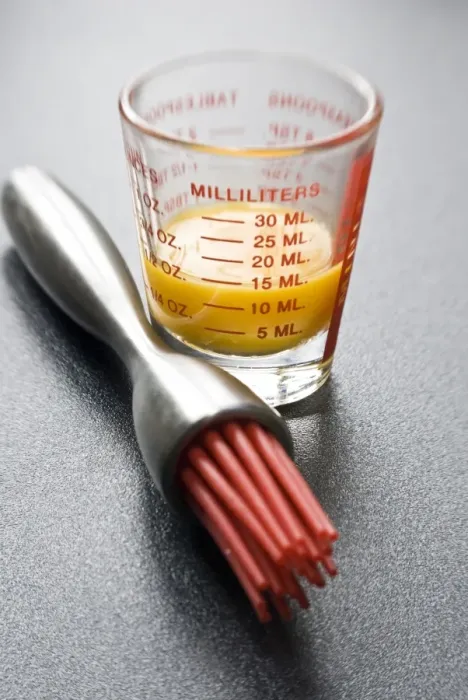 Framed Print : Egg yolk in small glass measuring glass with modern pastry brush with red silicone