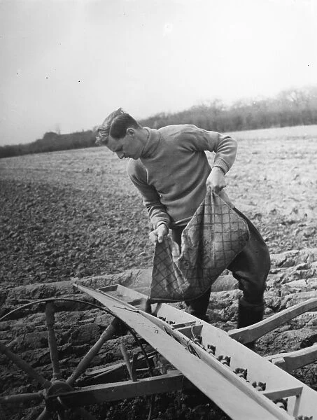 Farmer loading seeds from a sack into a Coopers Drymac seed barrow
