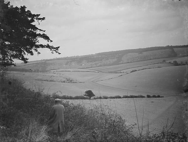 A farmer stands to view his fields at Preston hill farm estate. 3 February 1938