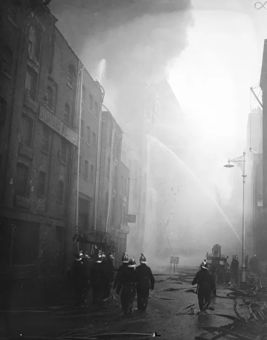 Framed Print : Firemen wallow in molten rubber as warehouse blazes still. Firemen wading through