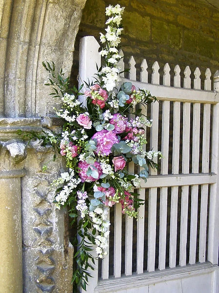 Flower arrangement decorating entrance to country church for summer wedding. credit