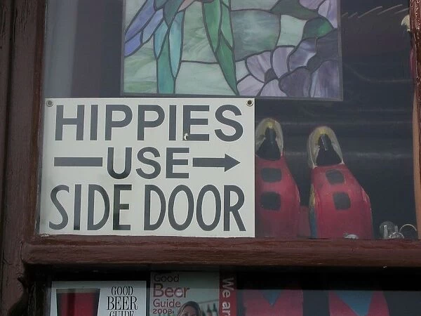 Humorous notice in window of pub: Hippies use side door, Deal, Kent, England