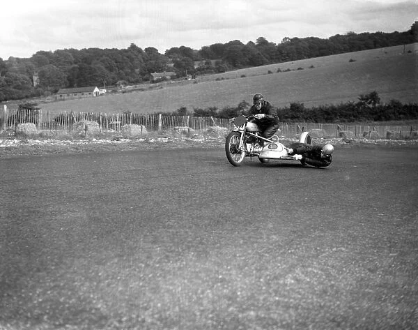 John Surtees hangs over the motorcycle side - car to balance the wheel as his father