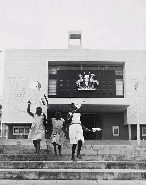 Kampala, Uganda, three young girls run down the steps in front of the new parliament