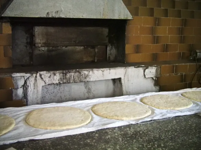 Framed Print : Large round flat loaves of bread rising on clean cloths on counter of quayside bakery