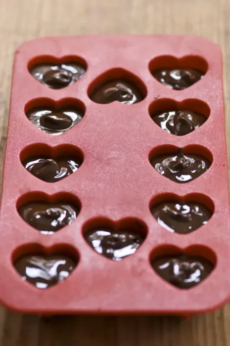 Framed Print : Making heart shaped in chocolates for Valentines day in red heart shaped mould credit Framed Print : Making heart shaped in chocolates for Valentines day in red heart shaped mould credit