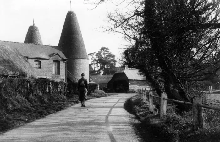 Framed Print : A man walks down a country road passing an oast house, near Penshurst, Kent, England