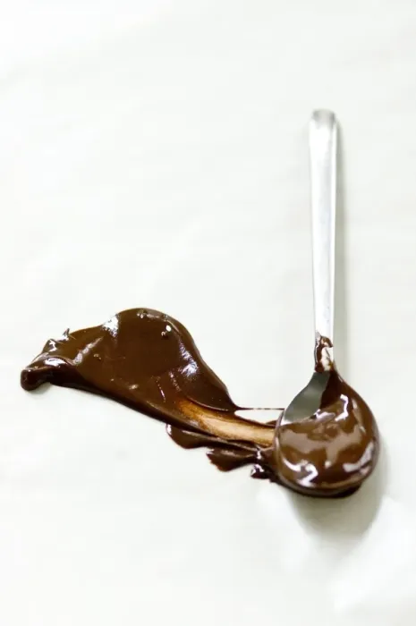 Framed Print : Melted chocolate smeared across white surface with a spoon leaving a plume shape Framed Print : Melted chocolate smeared across white surface with a spoon leaving a plume shape