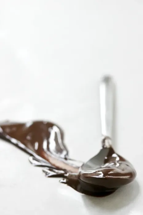 Framed Print : Melted chocolate smeared across white surface with a spoon leaving a plume shape