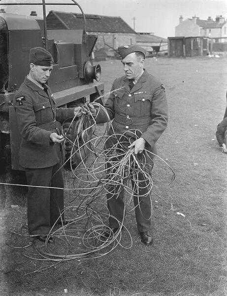 Two men examine storm damage in the form of broken cable at a balloon barrage base