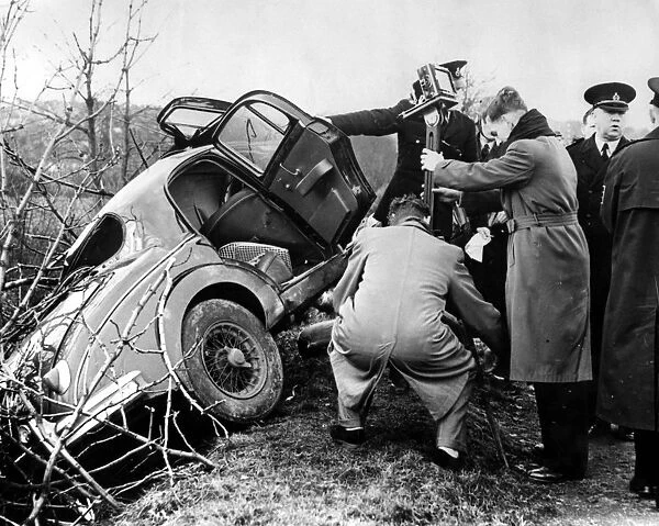 Police and photorgraphers are seen with the wreck of the black Jaguar car in which