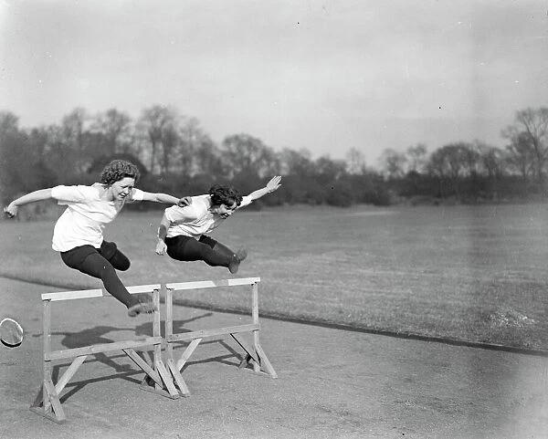 Preparing for the Olympic Games. Miss Hatt ( left ) and Miss Wright taking a hurdle