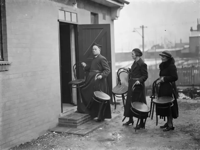 Framed Print : The Reverend M Cox moving chairs with some of his parishioners in Swanscombe, Kent Framed Print : The Reverend M Cox moving chairs with some of his parishioners in Swanscombe, Kent
