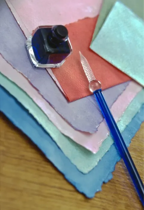 Framed Print : Selection of pastel coloured handmade papers with glass pen and small bottle of ink Framed Print : Selection of pastel coloured handmade papers with glass pen and small bottle of ink