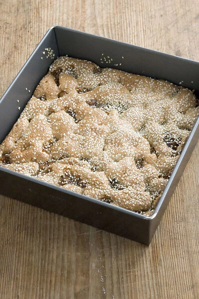 Semolina cake with figs and sesame still in its square tray on the kitchen table credit