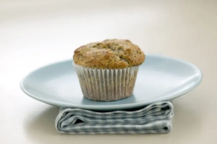 Framed Print : Single poppyseed muffin on blue plate on check napkin, on painted table. credit