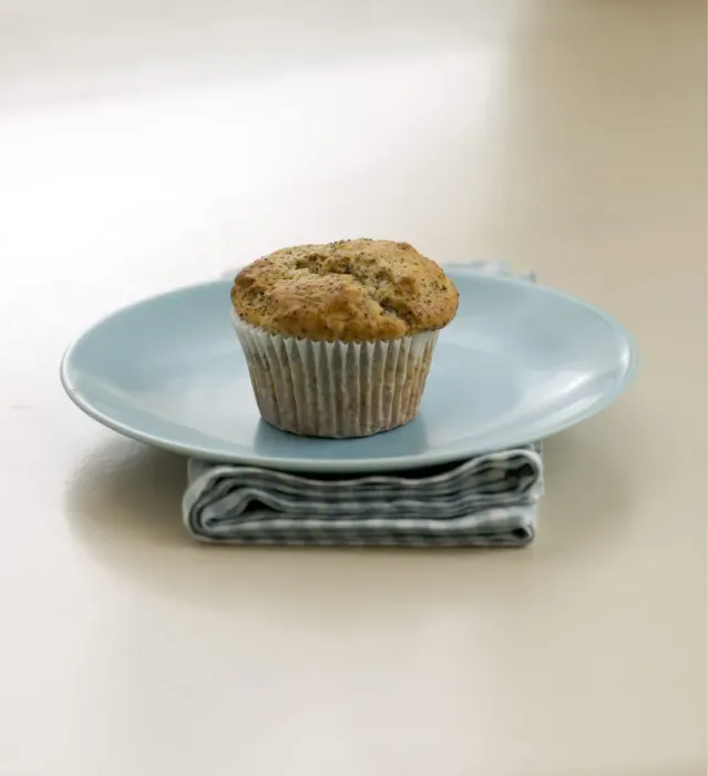 Framed Print : Single poppyseed muffin on blue plate on check napkin, on painted table. credit