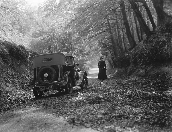 A woman taking in the woodland scene next to a parked sports car. 1936