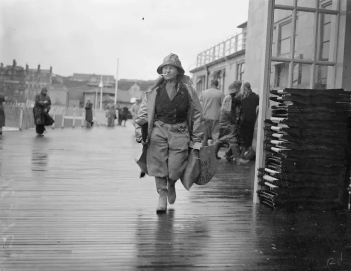 Framed Print : Women angler defies the gales at Hastings. With a stiff gale whipping up the sea