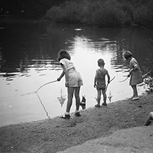 Children play with toy sailing boats in Dartford park. 24 August 1937