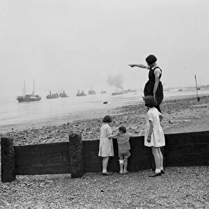 Children stand on the sea defences at Gravesend river front and look out over the
