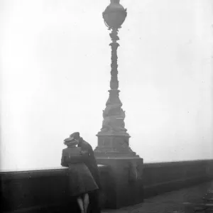 Couple arm in arm leaning over bridge in London in fog 1940s love couple romance Couple arm in arm leaning over bridge in London in fog 1940s love couple romance