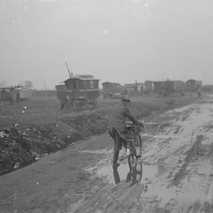 A cyclist on a muddy road with gypsy caravans, 1936 print