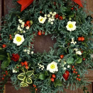 Evergreen christmas wreath with white christmas roses, rosehips, everlasting flowers