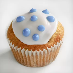 Iced cupcake with blue spots on white icing credit: Marie-Louise Avery / thePictureKitchen
