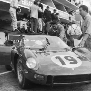 John Surtees bends under the driving wheel of his Ferrari here last night after he