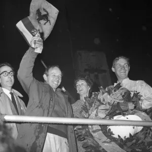 John Surtees smiles as he waves his trophy from the Victory Rostrum after he had