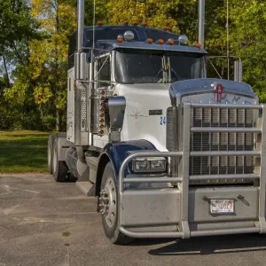 Unidad semitractor Kenworth 6x4 aparcada en el sol frente a colores de otoño hermosos. Unidad semitractor Kenworth 6x4 aparcada en el sol frente a colores de otoño hermosos.