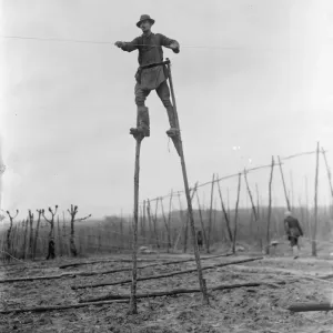 Print of a man using stilts to string hop poles in 1937