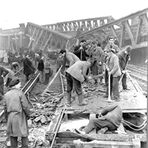 A man works with an acetylene cutting the remains of a train carriage in the foreground