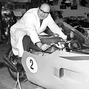 A mechanic sits astride John Surteess racing MV Augusta motorbike inside the Surtees