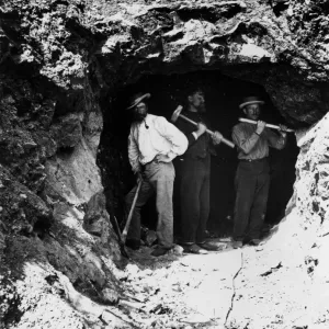 Three men standing in a tunnel, these men have just begun to bore one of three tunnels