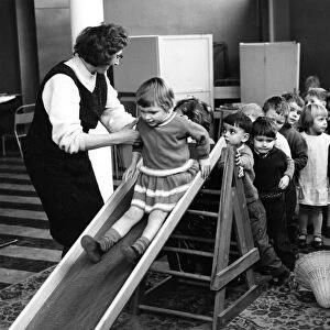 Mrs Joan Edison, leader of the nursery, helping her young charges on the slide