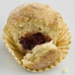 Muffin with sugary top filled with jam (jelly), broken open to show filling. A muffin Muffin with sugary top filled with jam (jelly), broken open to show filling. A muffin