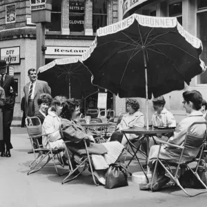 Office girls take their lunch break al fresco in a continental style table and umbrella Office girls take their lunch break al fresco in a continental style table and umbrella